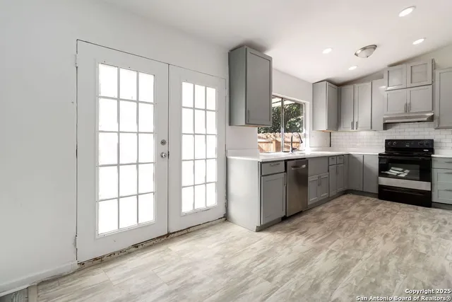 a kitchen with stainless steel appliances a sink window and cabinets