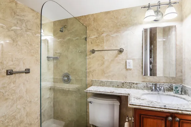 a bathroom with a granite countertop sink a mirror and shower