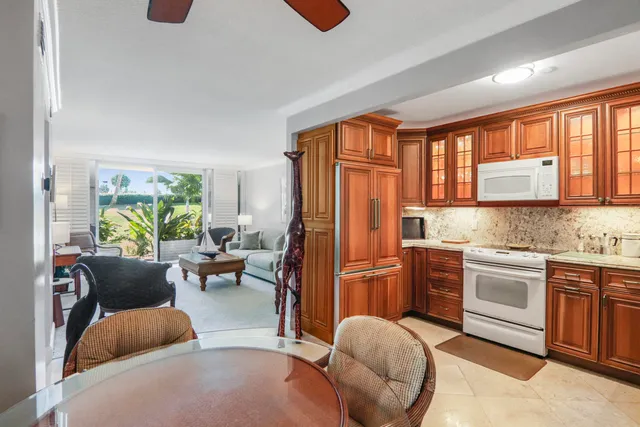 a kitchen with stainless steel appliances granite countertop a refrigerator a stove a sink dishwasher and couches with wooden floor