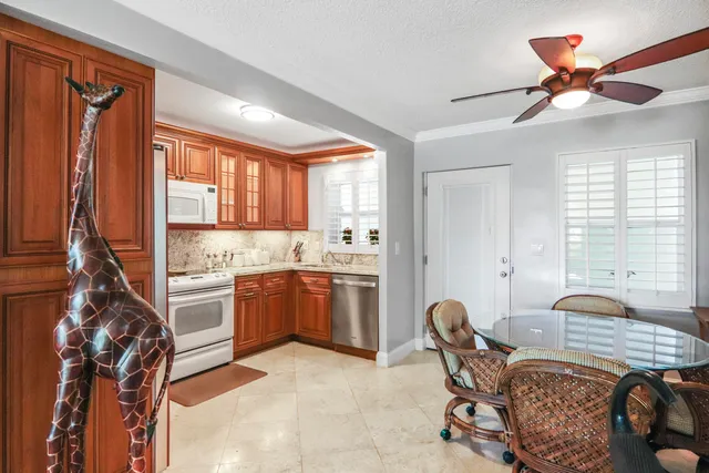 a kitchen with a refrigerator a stove a sink dishwasher a dining table and chairs with wooden floor