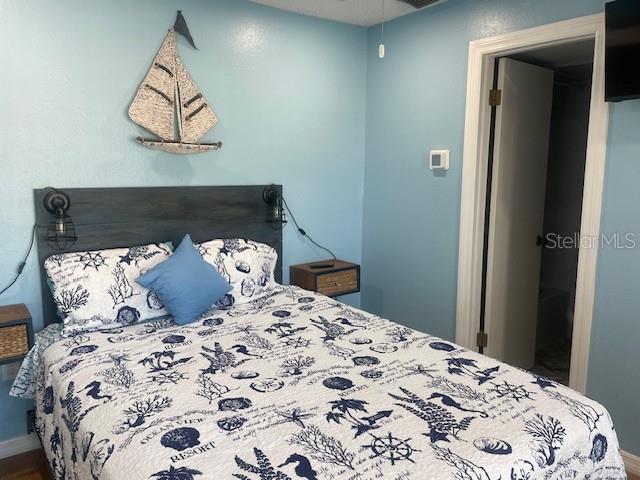 159 Medallion Boulevard, Unit E Madeira Beach, FL 33708 - Photo 12 of 15 a bed sitting in a bedroom next to a window and a wooden floor