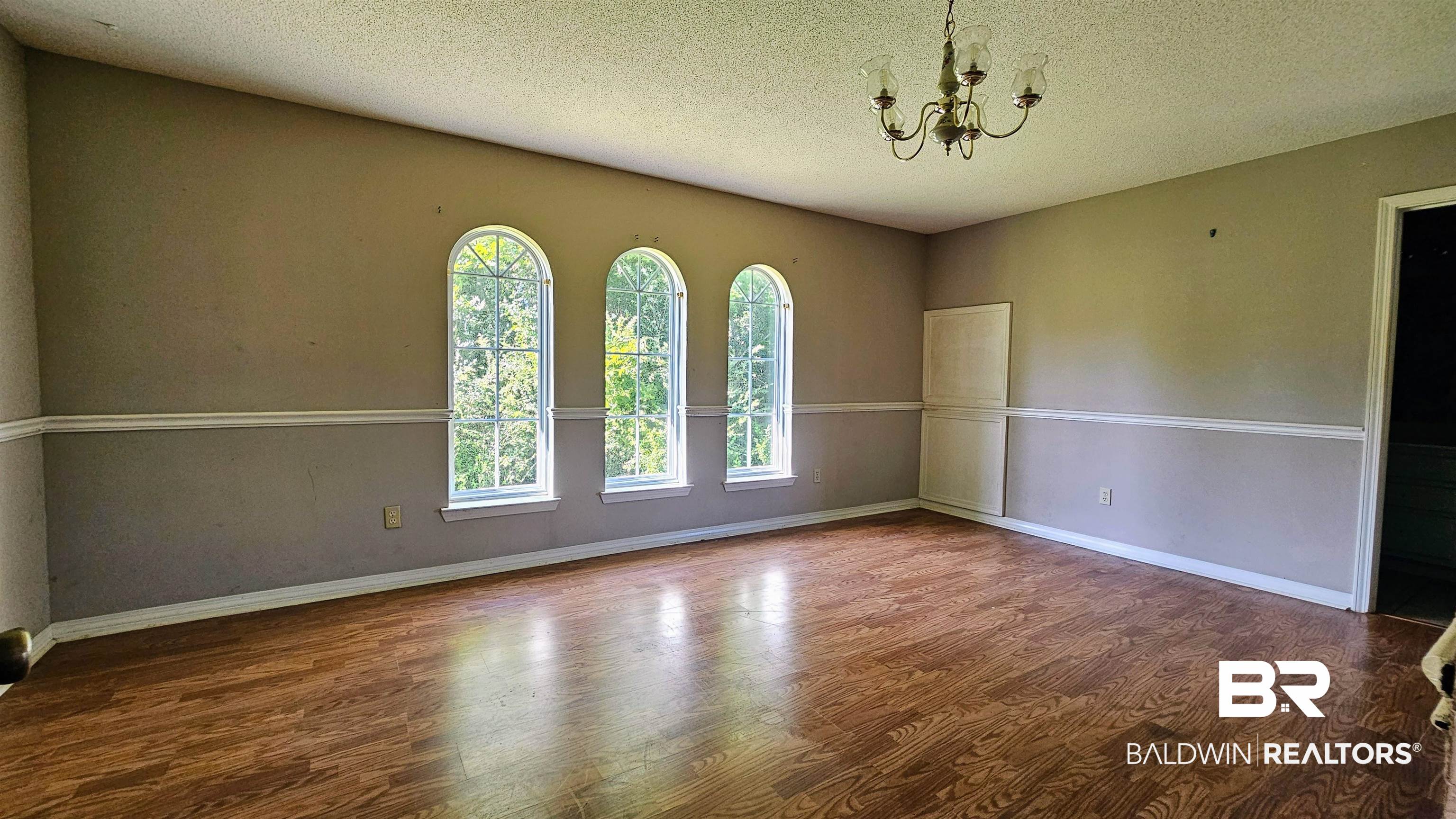 18824 Highway 41 Brewton, AL 36426 - Photo 30 of 40 Spacious room featuring wood-finish flooring, a decorative chandelier, and three arched windows providing natural illumination