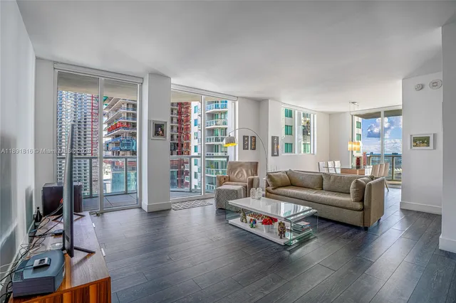 a living room with furniture a flat screen tv and a floor to ceiling window