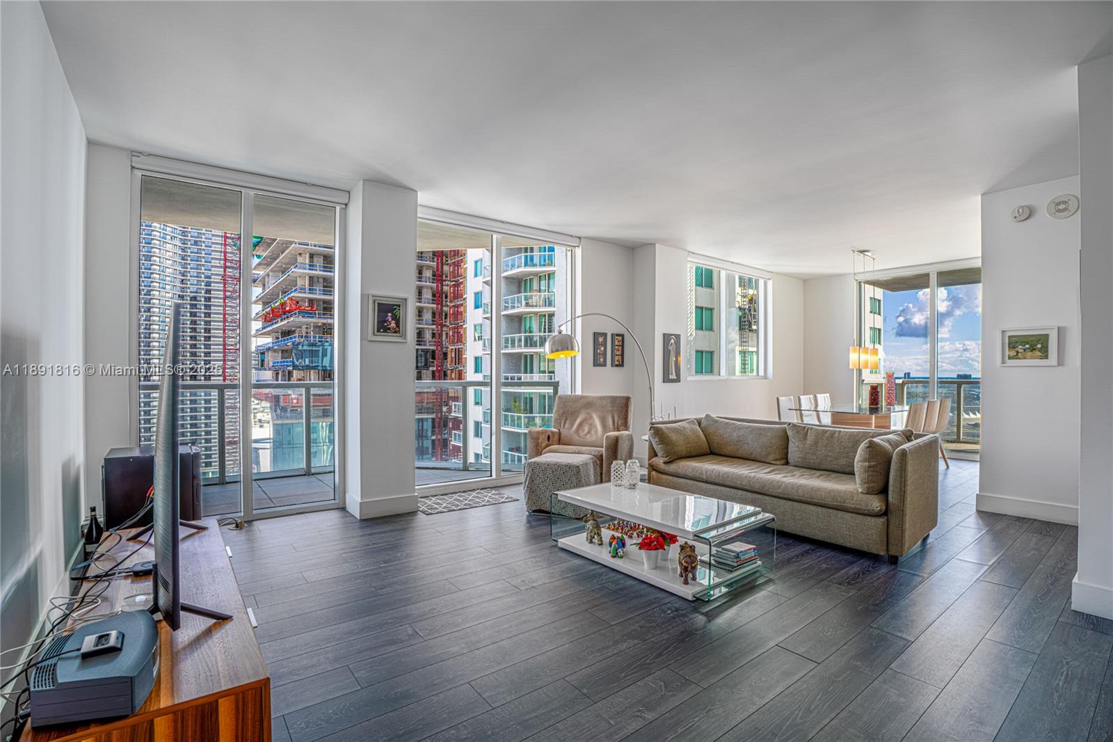 253 Northeast 2nd Street, Unit 3203 Miami, FL 33132 - Photo 2 of 29 a living room with furniture a flat screen tv and a floor to ceiling window