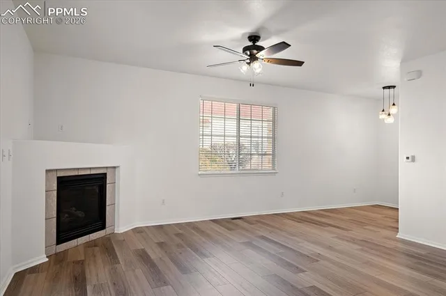 a view of an empty room with wooden floor and a fireplace