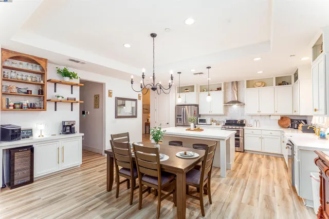 a view of a kitchen with kitchen island stainless steel appliances wooden floor dining table and chairs