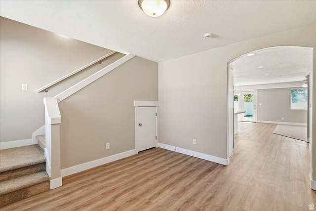 857 225 South Springville, UT 84663 - Photo 2 of 23 Entry area featuring wood-finish flooring, a carpeted staircase with white railing, and an arched entryway leading to an open concept living space