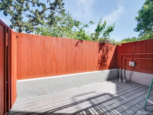a view of backyard with wooden fence and large trees