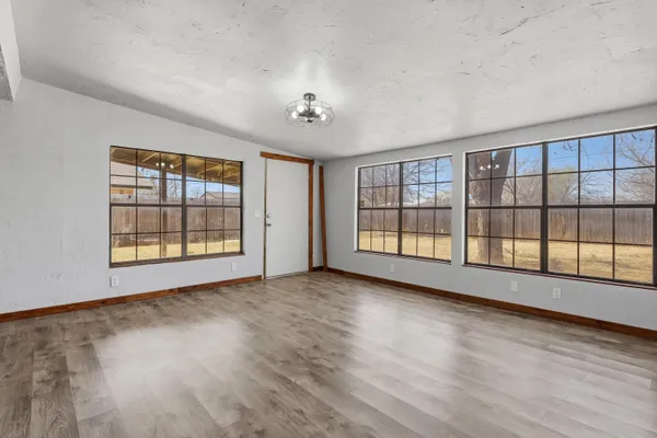 a view of an empty room with a window and wooden floor