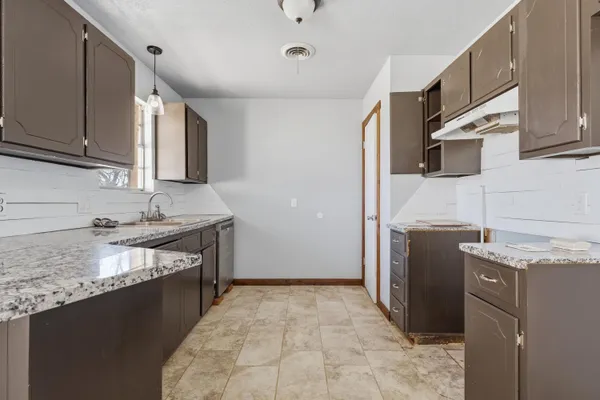 a kitchen with granite countertop a sink stove and refrigerator