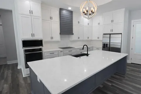 a kitchen with kitchen island granite countertop a sink a counter space and cabinets