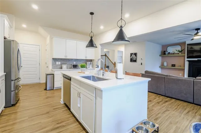 a kitchen with kitchen island a counter top space a sink stainless steel appliances and cabinets