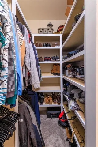 a view of walk in closet with clothes and shoes