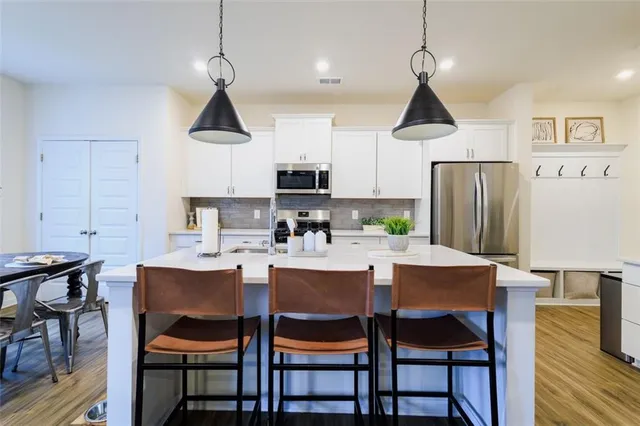 a dining room with stainless steel appliances granite countertop a dining table chairs and a refrigerator