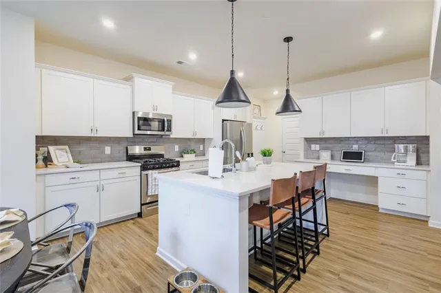 a kitchen with stainless steel appliances kitchen island granite countertop a stove a sink a dining table and chairs