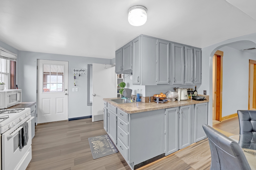 54 Airport Road Fitchburg, MA 01420 - Photo 14 of 38 a kitchen with stainless steel appliances granite countertop a stove top oven a sink dishwasher and white cabinets with wooden floor