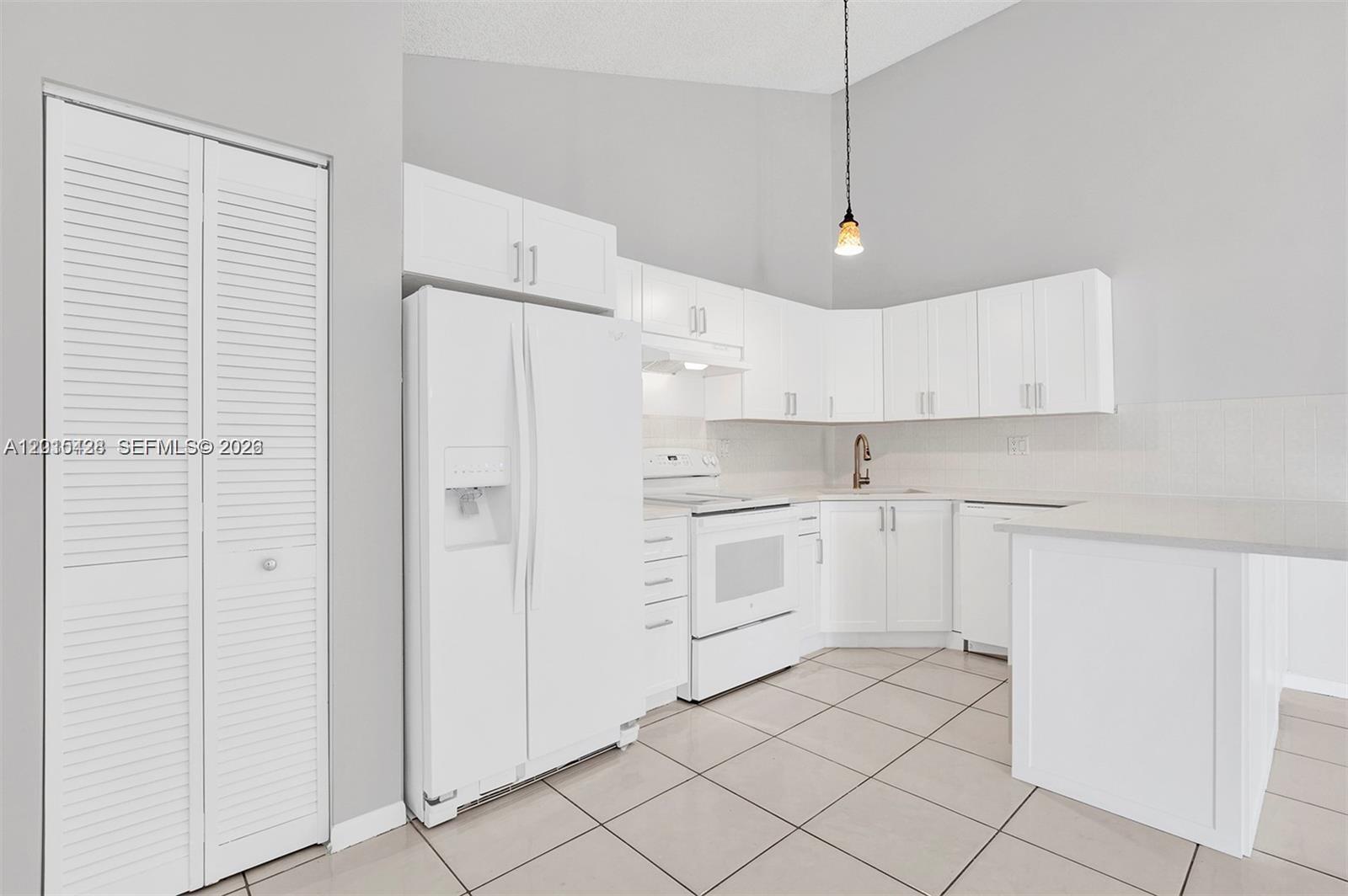 9892 Boca Gardens Parkway, Unit A Boca Raton, FL 33496 - Photo 8 of 32 a kitchen with white cabinets and white appliances
