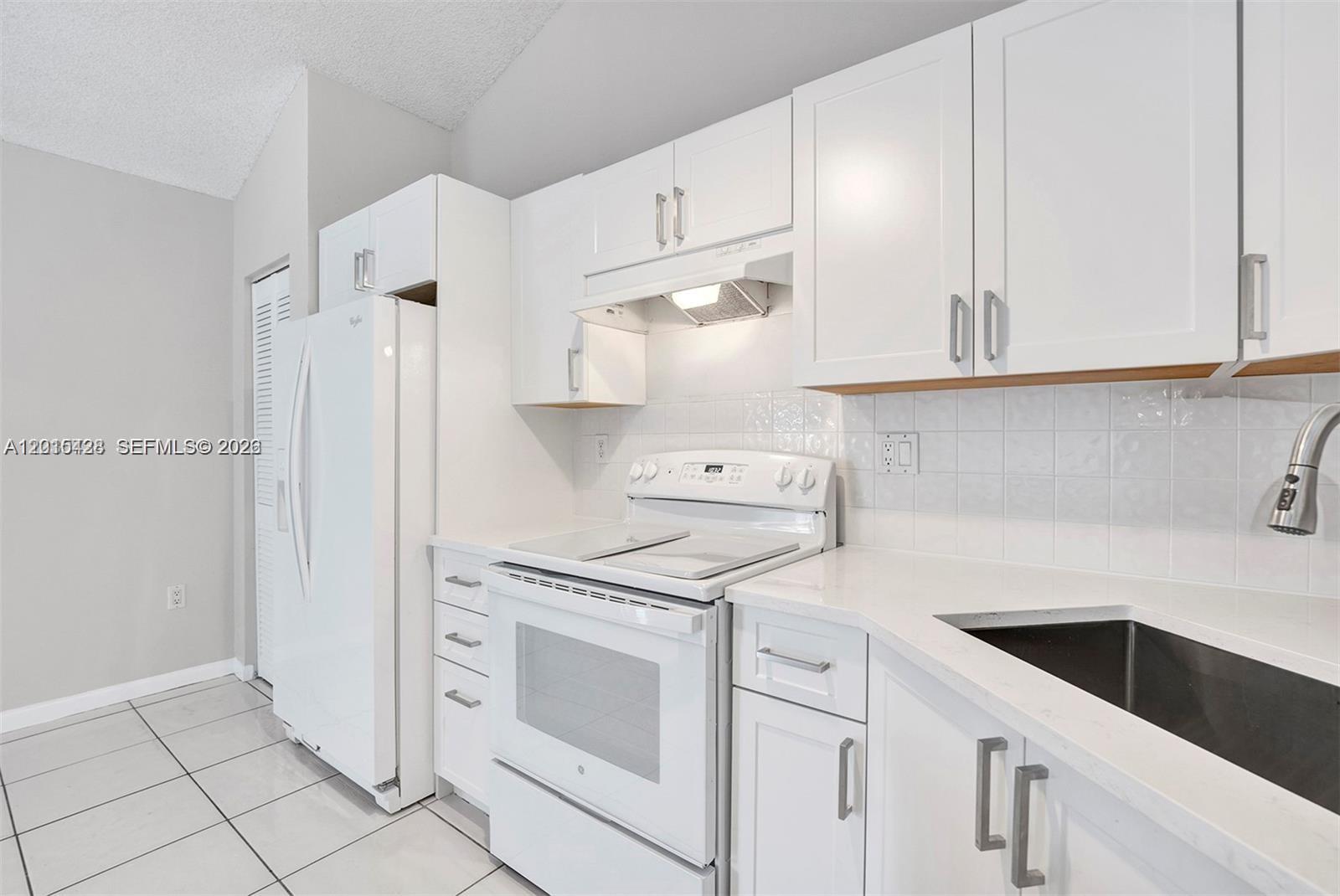 9892 Boca Gardens Parkway, Unit A Boca Raton, FL 33496 - Photo 10 of 32 a kitchen with cabinets appliances and a sink