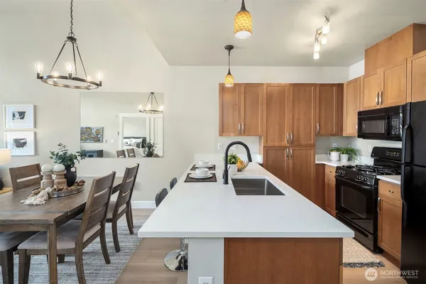 a kitchen with stainless steel appliances granite countertop a sink a stove a refrigerator cabinets a dining table and chairs