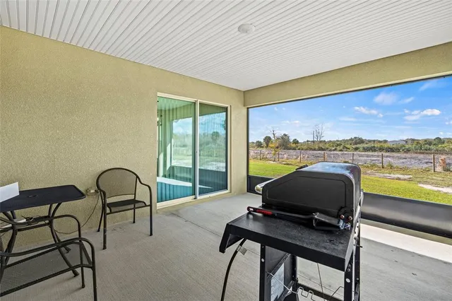 a living room with furniture and floor to ceiling window next to a yard