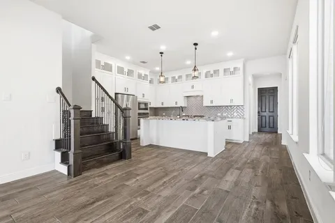 a large white kitchen with cabinets and wooden floor