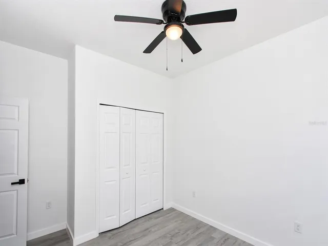 a view of a room with wooden floor and a ceiling fan