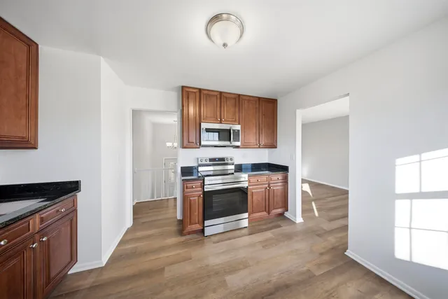 a kitchen with granite countertop a stove and a wooden floors