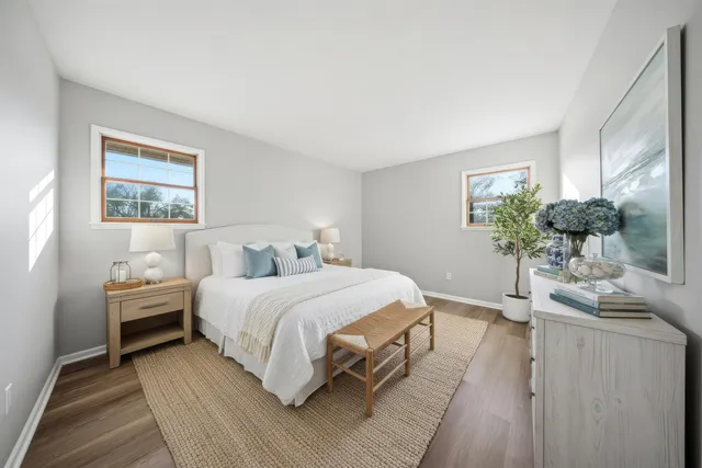 a bedroom with a bed table flowerpot and window