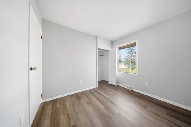 an empty room with wooden floor and windows