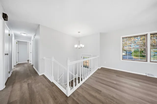 a view of a hallway with wooden floor and windows