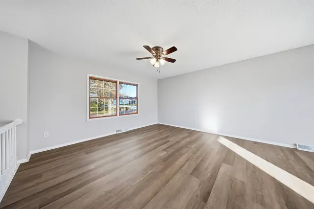 an empty room with wooden floor and windows