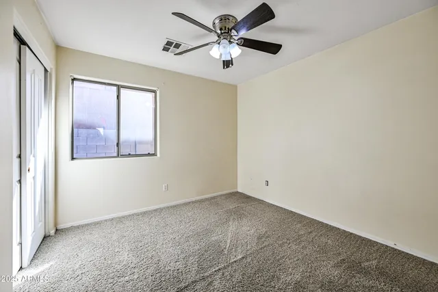 an empty room with a window and a fan
