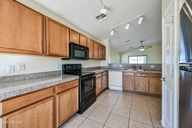 a kitchen with stainless steel appliances granite countertop a sink dishwasher stove and refrigerator with wooden cabinets