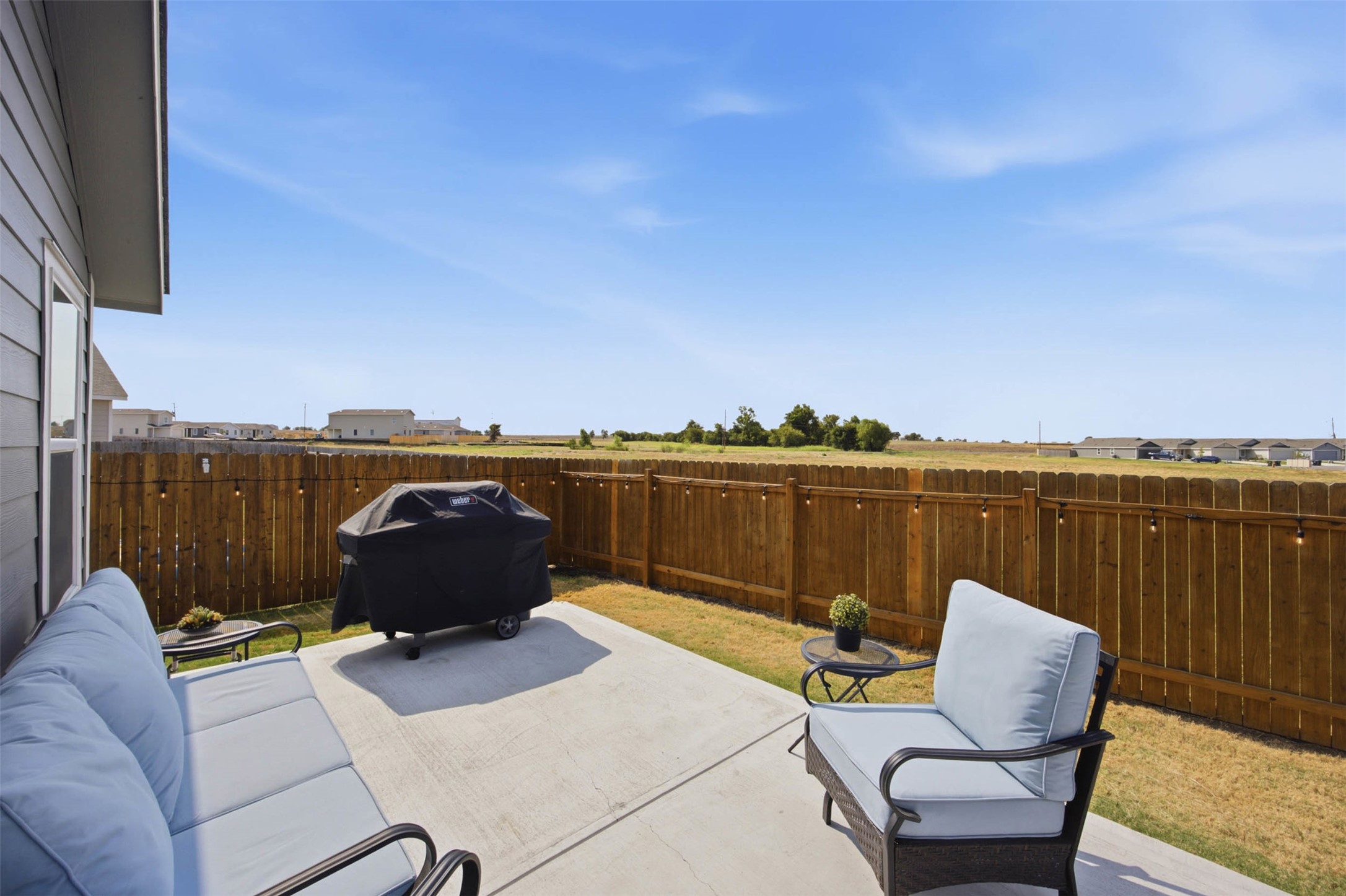 171 Cattle Queen Road Jarrell, TX 76537 - Photo 27 of 38 A concrete patio looks out over a fenced yard toward an open grassy horizon.