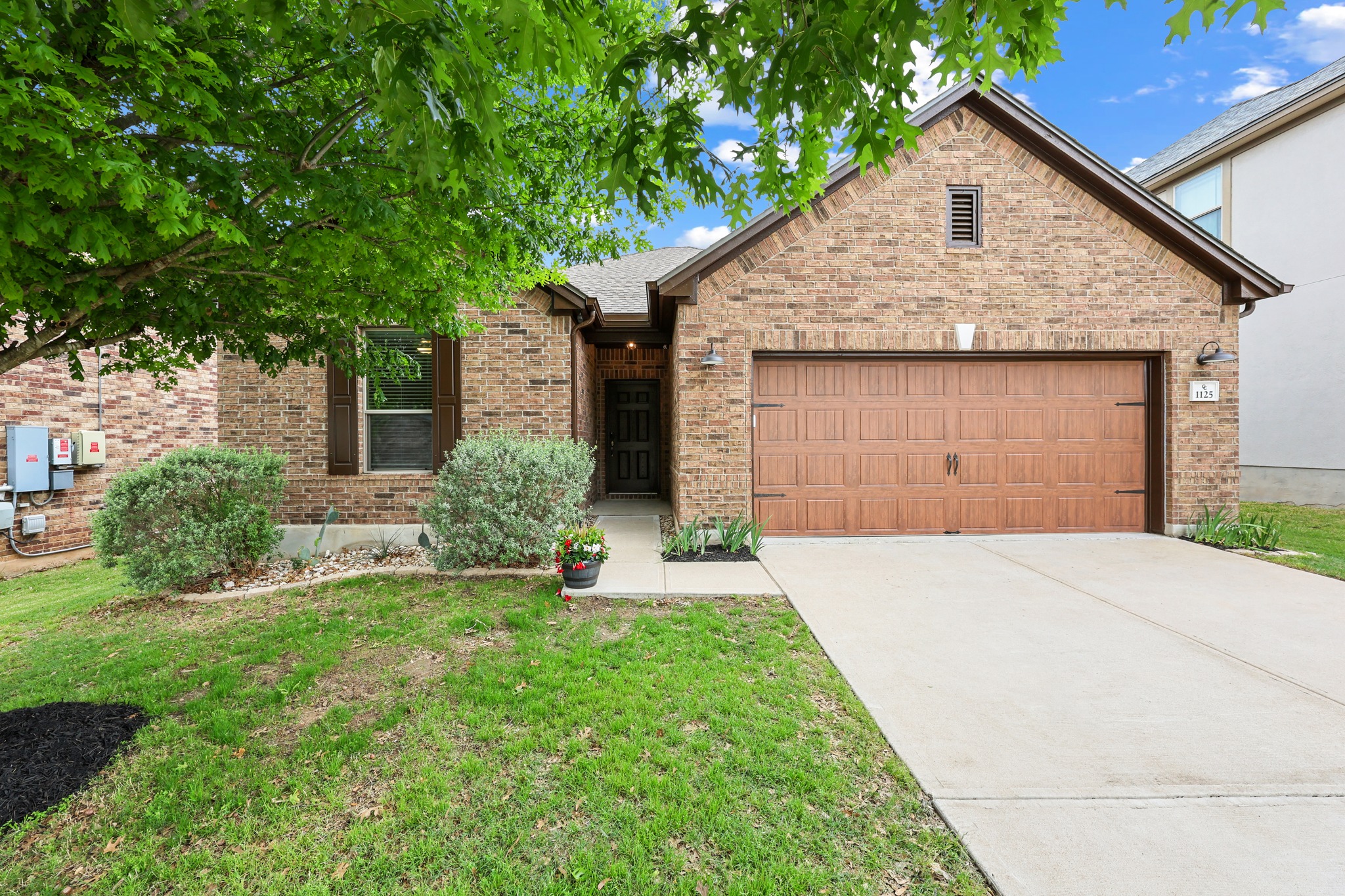 View of front of home featuring a garage, concrete driveway, brick siding, and a front lawn
