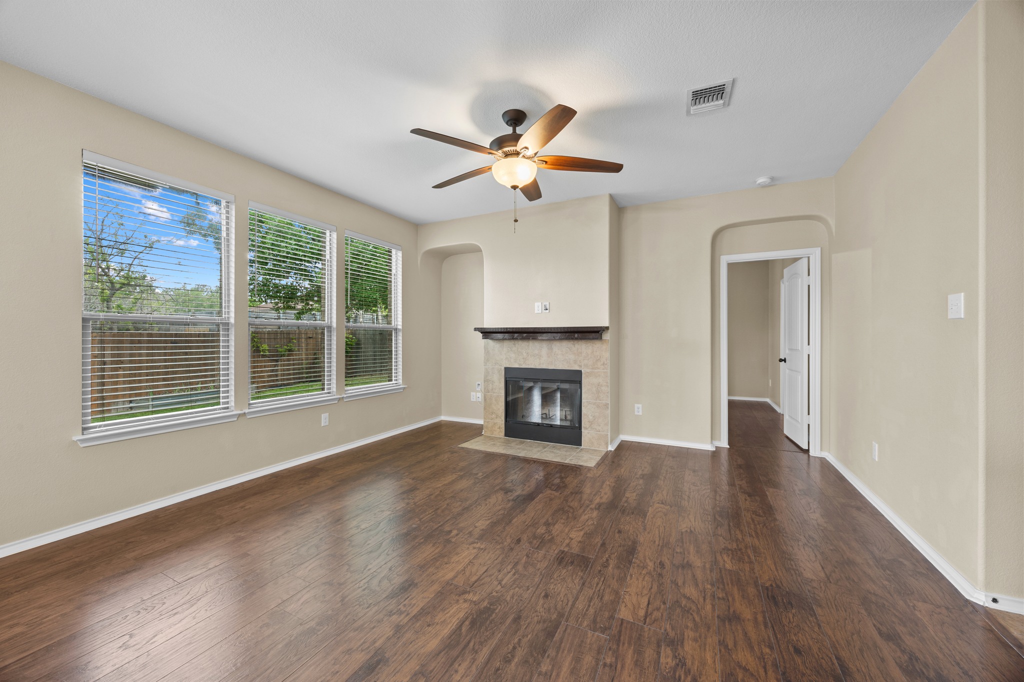 1125 Yellow Iris Road Leander, TX 78641 - Photo 13 of 31 Unfurnished living room featuring ceiling fan, a fireplace with flush hearth, dark wood-type flooring, and arched walkways