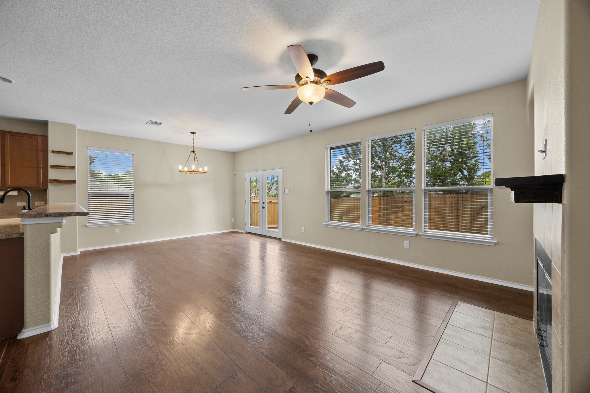 1125 Yellow Iris Road Leander, TX 78641 - Photo 14 of 31 Unfurnished living room featuring ceiling fan, hanging lights, dark wood finished floors, and a fireplace with flush hearth