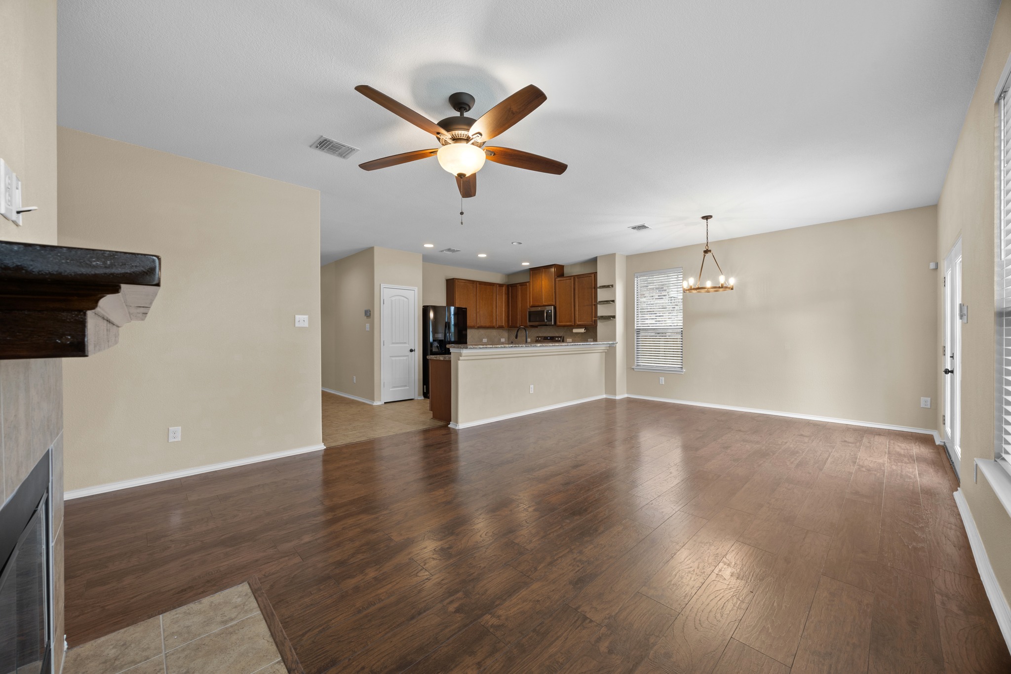 1125 Yellow Iris Road Leander, TX 78641 - Photo 15 of 31 Unfurnished living room featuring a tiled fireplace, dark wood-type flooring, suspended lighting, and ceiling fan
