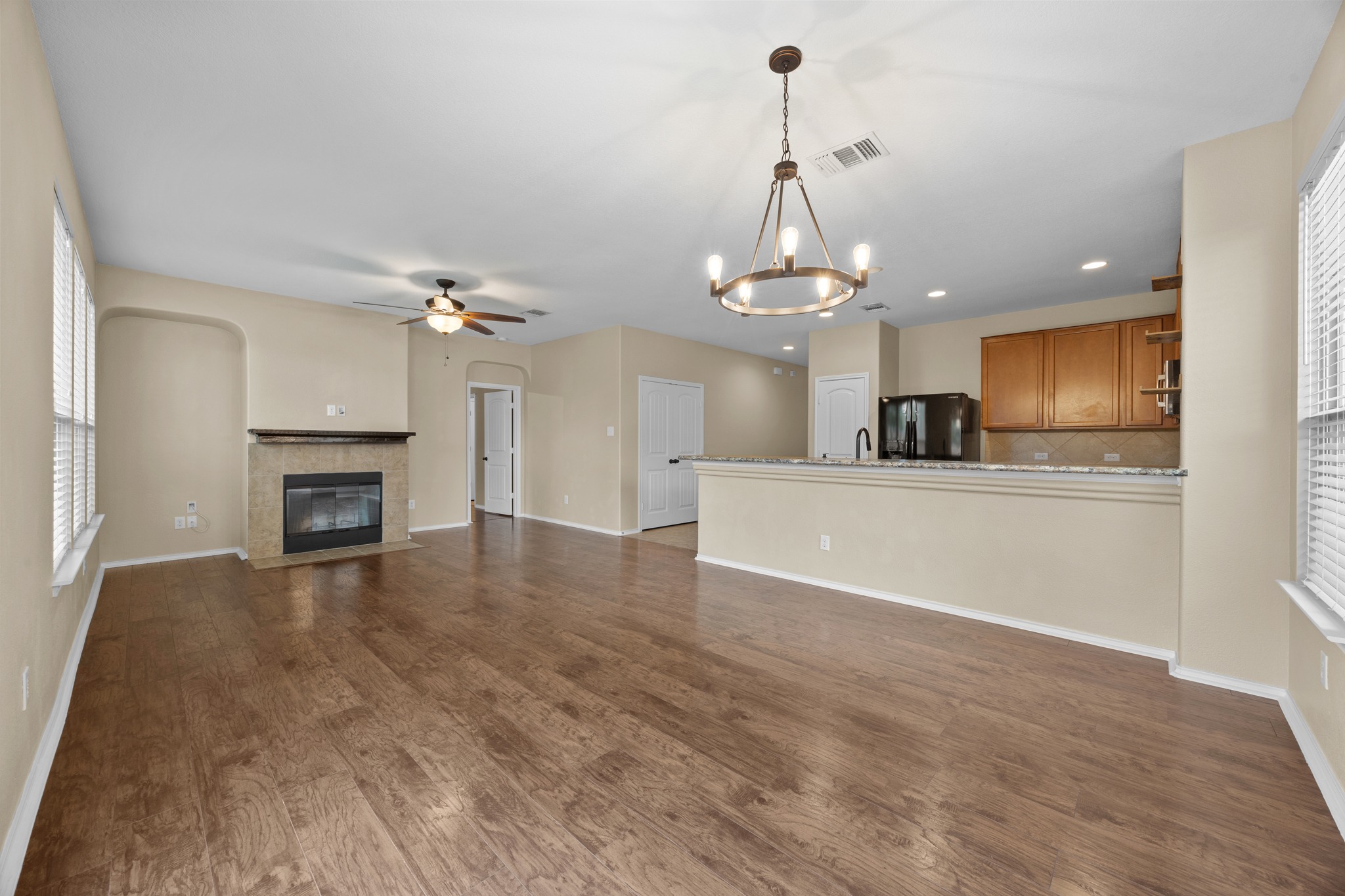 1125 Yellow Iris Road Leander, TX 78641 - Photo 17 of 31 Unfurnished living room featuring a fireplace with flush hearth, ceiling fan, dark wood-style flooring, and hanging lights