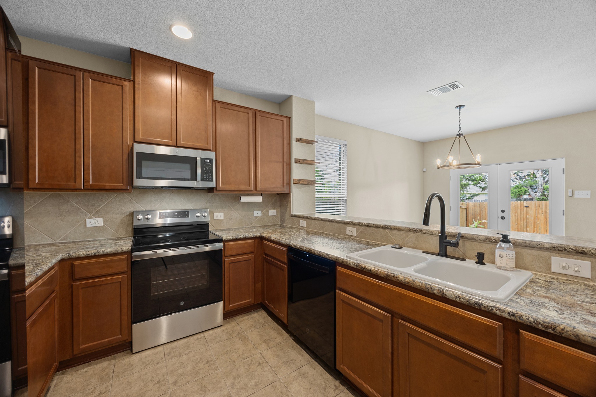 1125 Yellow Iris Road Leander, TX 78641 - Photo 20 of 31 Kitchen featuring a chandelier, stainless steel appliances, wood finish cabinets, french doors, and healthy amount of natural light