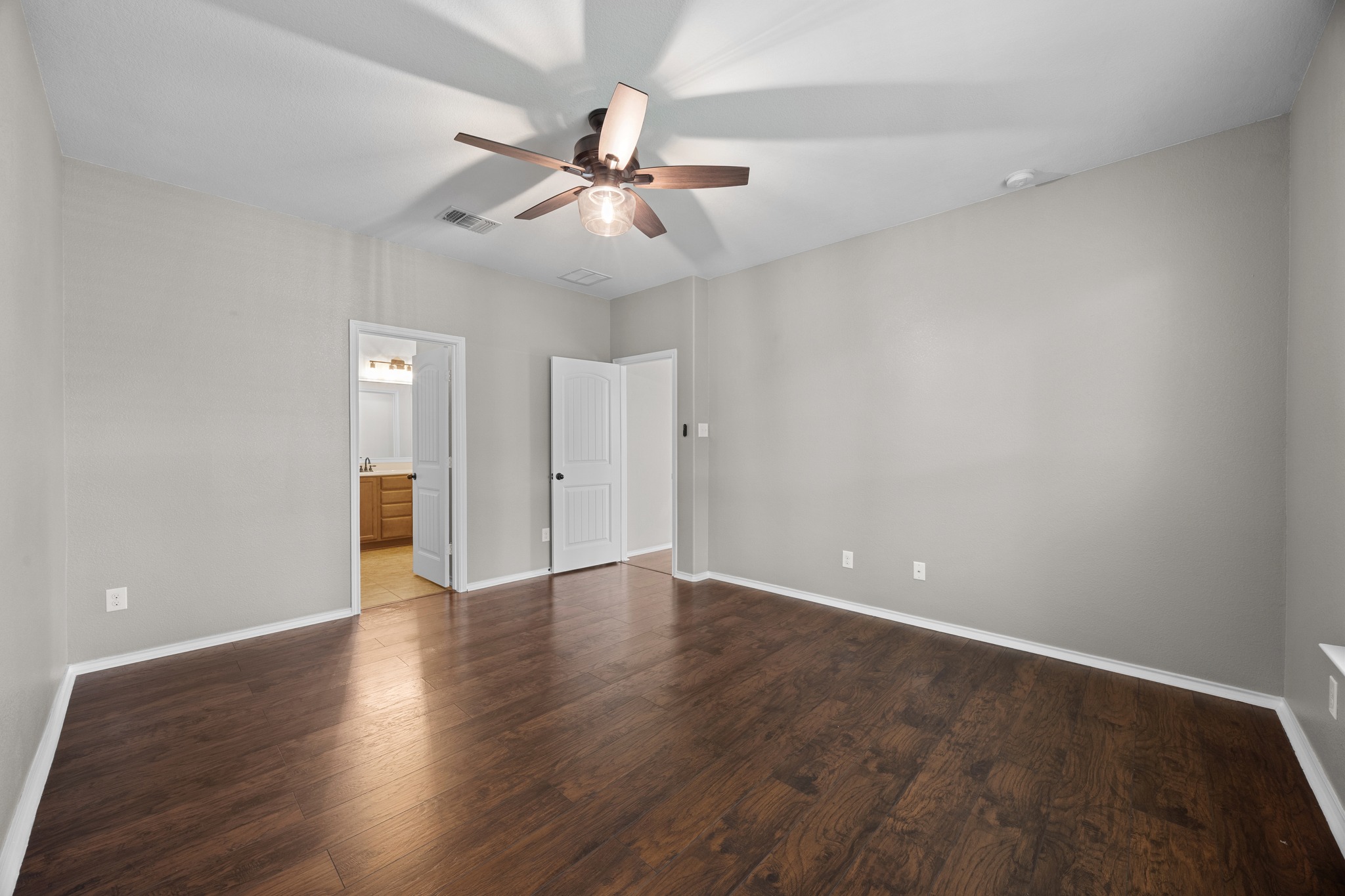 1125 Yellow Iris Road Leander, TX 78641 - Photo 24 of 31 Unfurnished bedroom featuring a ceiling fan, dark wood-style flooring, and ensuite bathroom