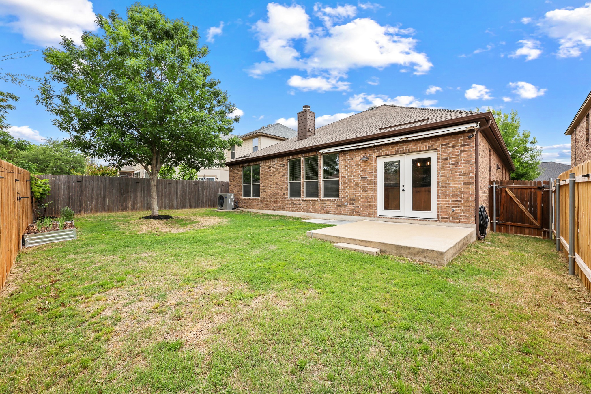 1125 Yellow Iris Road Leander, TX 78641 - Photo 28 of 31 Back of property featuring brick siding, a patio area, a fenced backyard, a gate, and french doors