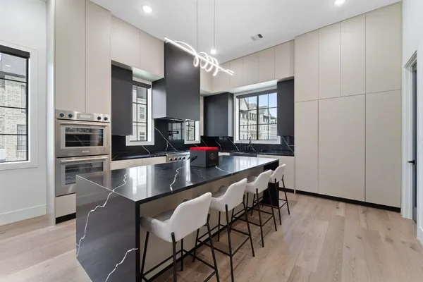 a kitchen with stainless steel appliances granite countertop a stove a refrigerator a sink a dining table and chairs with wooden floor