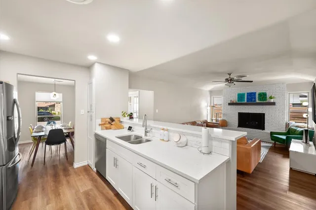 a large white kitchen with a stove a sink dishwasher and a fireplace with wooden floor