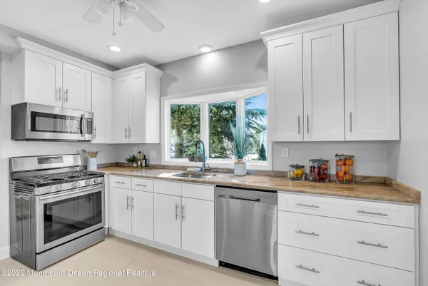 a kitchen with white cabinets appliances a sink and a window