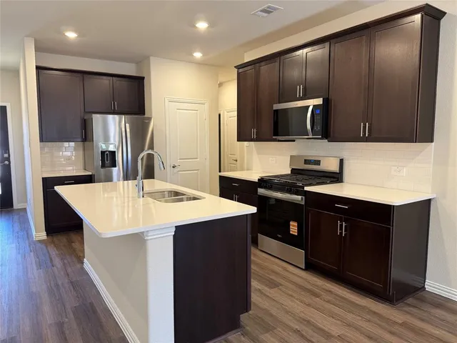 a kitchen with stainless steel appliances kitchen island granite countertop a sink refrigerator and microwave