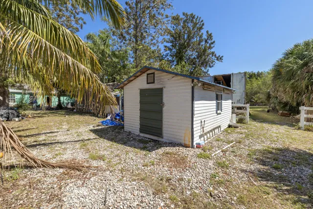 a view of a house with a small yard and large trees