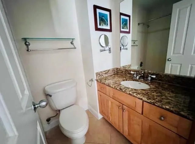 a bathroom with a granite countertop toilet sink and mirror