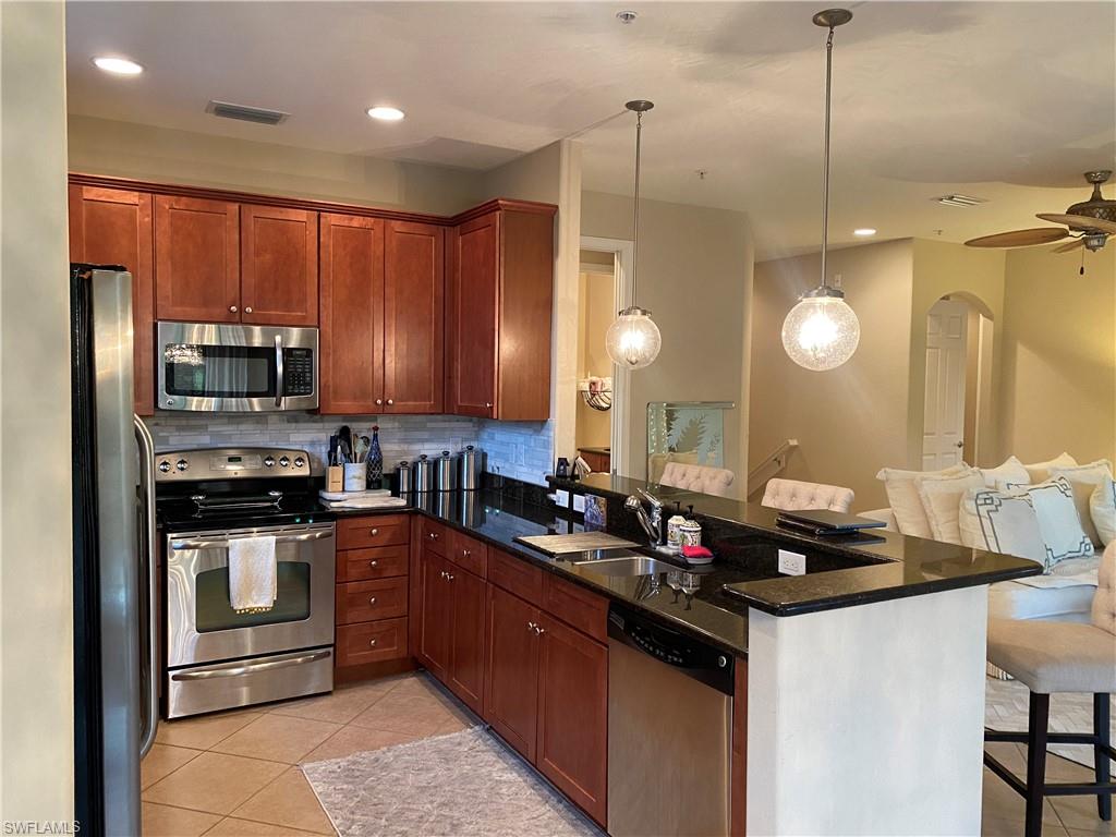 8997 Cambria Circle, Unit 2002 Naples, FL 34113 - Photo 35 of 35 a kitchen with stainless steel appliances granite countertop a sink a stove and cabinets