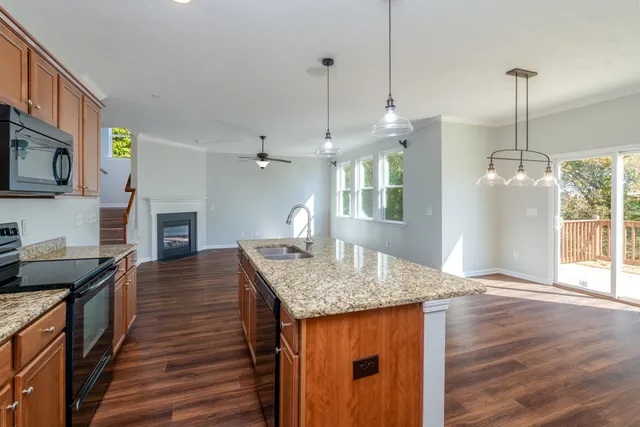 a kitchen with granite countertop a stove a sink a center island and wooden floor